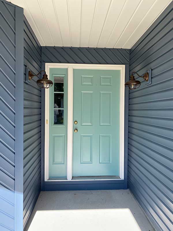 Finished exterior entry with slate blue siding and a repainted teal front door in Palm Bay, FL
