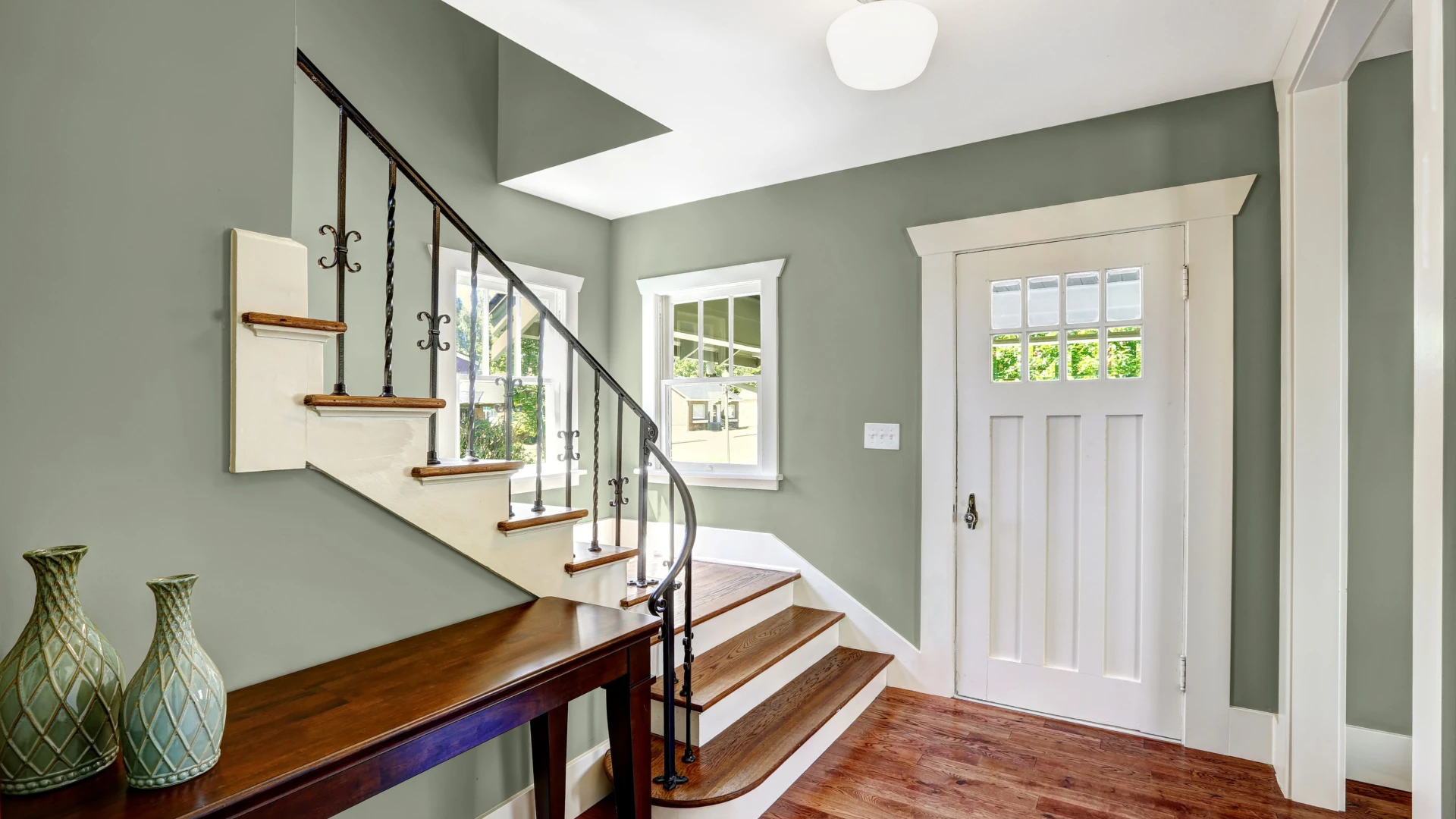 Finished entryway with sage green walls and bright white trim and stair risers in Viera, FL
