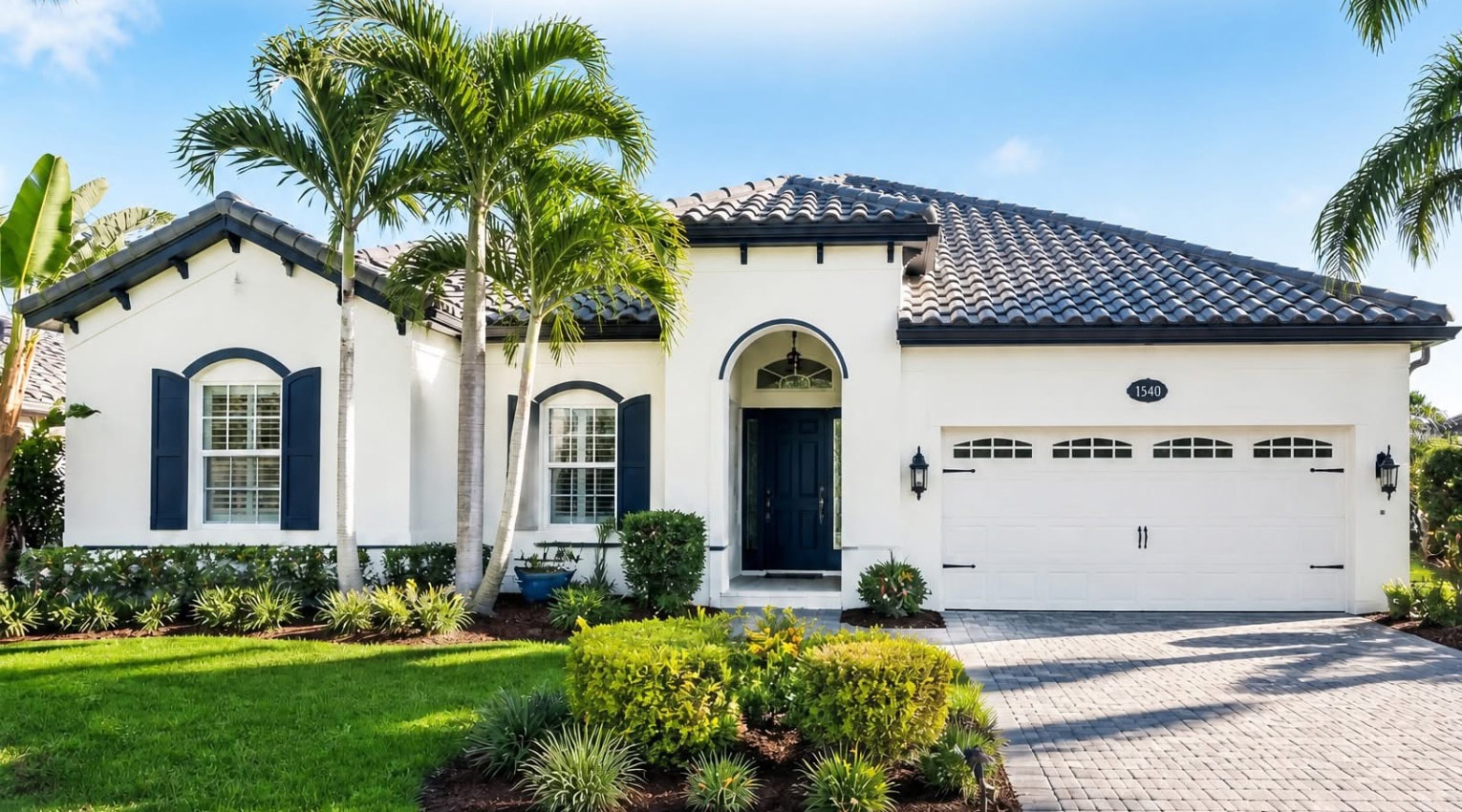 Freshly painted white stucco Florida home with navy shutters, a navy front door and a paver driveway in Brevard County