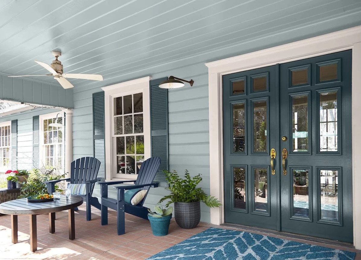 Finished front porch with sage siding, white trim and dark teal double doors in Cocoa Beach, FL