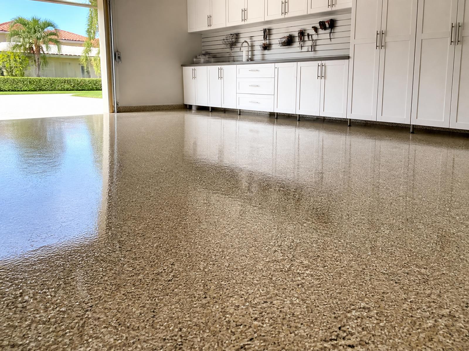Finished tan flake epoxy garage floor with white storage cabinets in Suntree, FL