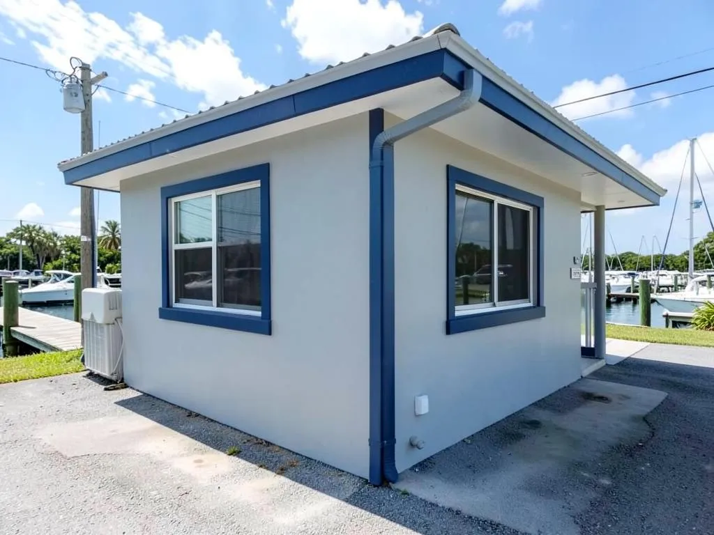 Freshly repainted light gray marina office building with navy trim beside boat docks in Port Canaveral, FL