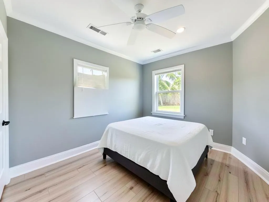 Finished bedroom painted soft greige with crisp white crown molding and baseboards in Melbourne Village, FL